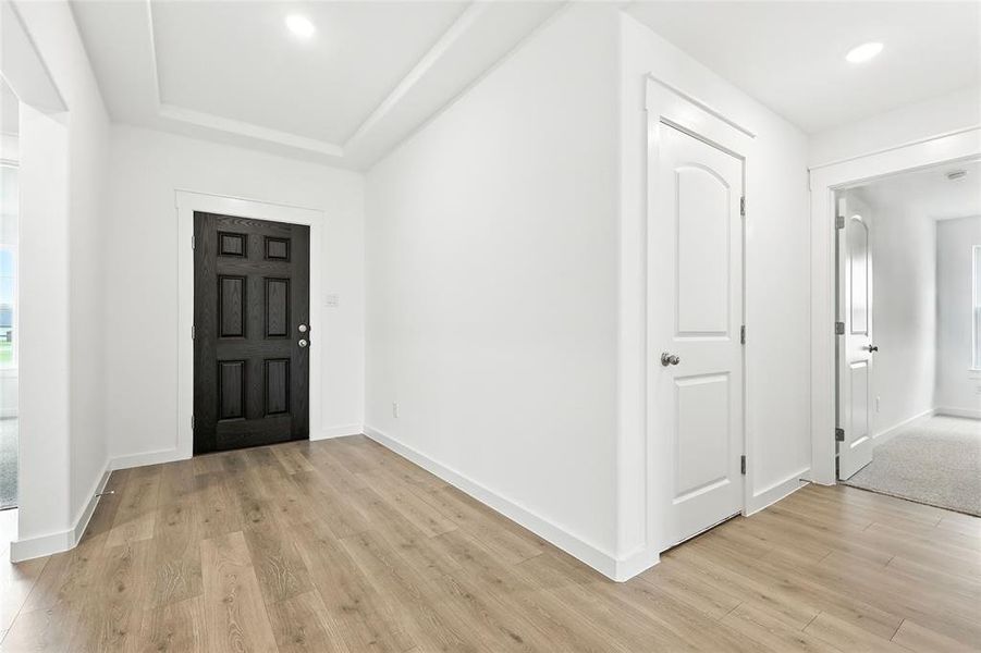 Entryway featuring light wood finished floors, recessed lighting, and a raised ceiling