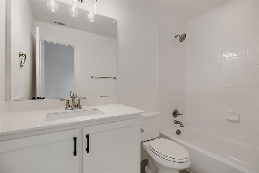 Bathroom featuring a white vanity with an integrated sink, brushed nickel faucet, and a large frameless mirror Bathroom featuring a white vanity with an integrated sink, brushed nickel faucet, and a large frameless mirror