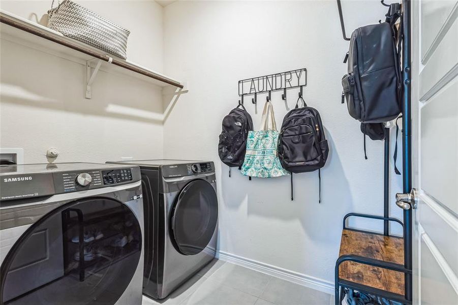 Washroom with tile patterned floors, laundry area, baseboards, and separate washer and dryer
