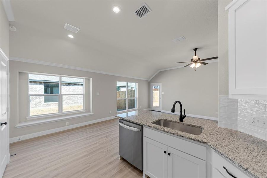 Kitchen with vaulted ceiling, stainless steel dishwasher, a peninsula, white cabinets, and ceiling fan