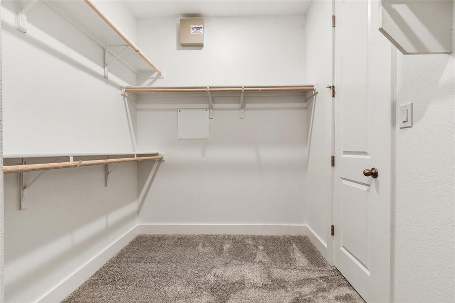 Functional and tidy, this walk-in closet offers ample storage with built-in shelving and hanging rods.