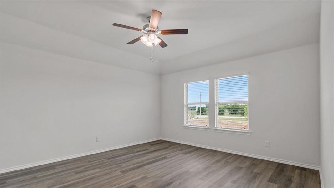 Spacious room featuring wood-finish flooring, white baseboards, and a ceiling fan with integrated lighting Spacious room featuring wood-finish flooring, white baseboards, and a ceiling fan with integrated lighting