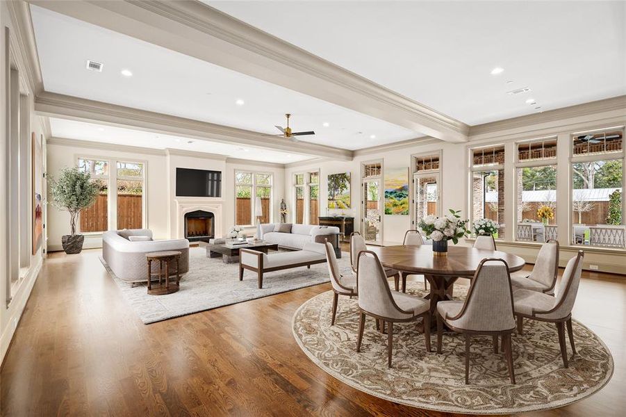 At the end of the entry gallery, the sprawling great room impresses with walls of windows, beamed ceilings, a ceiling fan, a fireplace, and access to the rear terrace. The spacious layout is ideal for both seating and casual dining areas.