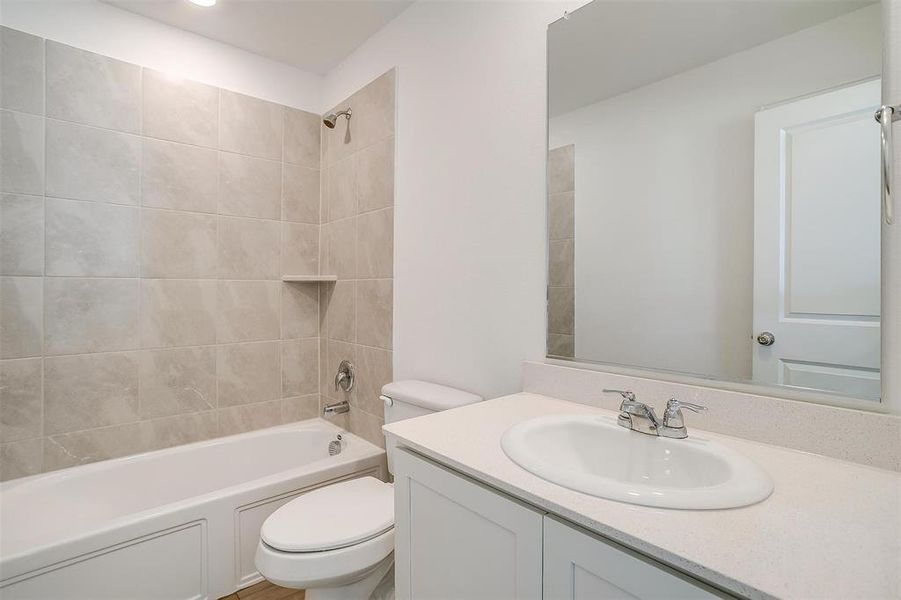 Full bathroom with tiled shower / bath combo, toilet, and vanity