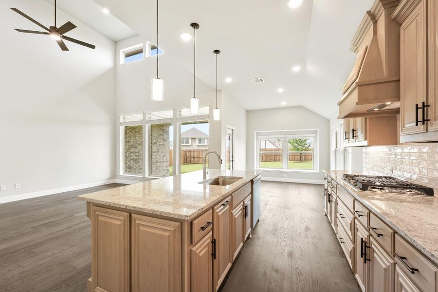 Kitchen with large island, granite countertops, wood cabinets, and vaulted ceiling with pendant lights Kitchen with large island, granite countertops, wood cabinets, and vaulted ceiling with pendant lights