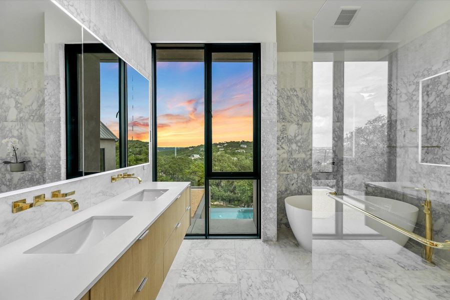 Bathroom with double vanity, a soaking tub, light marble finish flooring, and tile walls