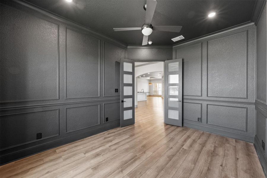 Spare room featuring visible vents, arched walkways, a ceiling fan, and a decorative wall