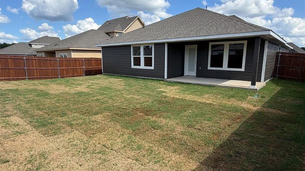 Expansive backyard featuring a privacy fence, concrete patio, and dark-toned siding