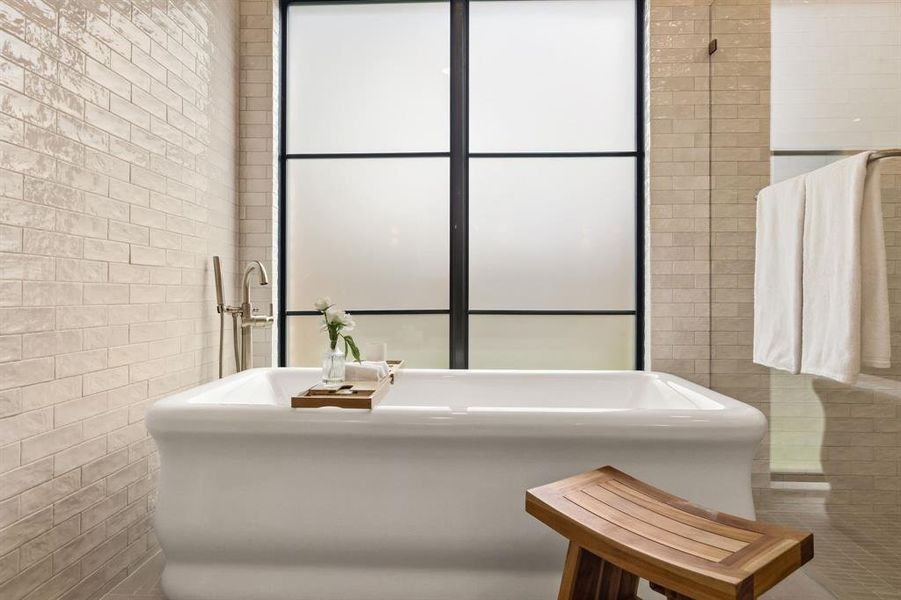 Freestanding soaking tub set against a frosted window with black grid detailing
