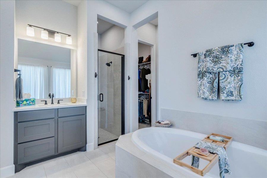 Bathroom with a shower stall, vanity, a walk in closet, light tile patterned flooring, and a bath