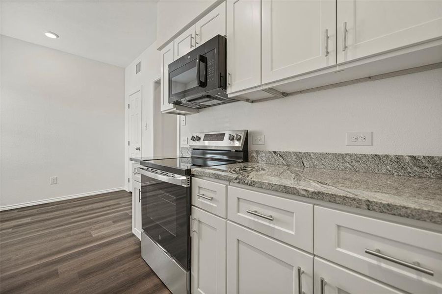 Kitchen featuring white cabinetry, dark hardwood / wood-style flooring, light stone countertops, and stainless steel electric range