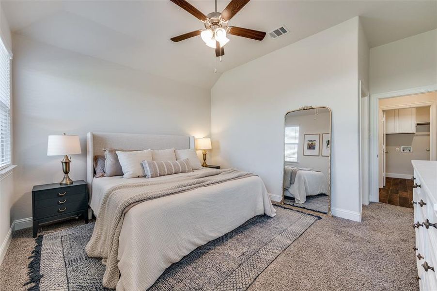 Primary bedroom with ceiling fan, carpet, and high ceiling