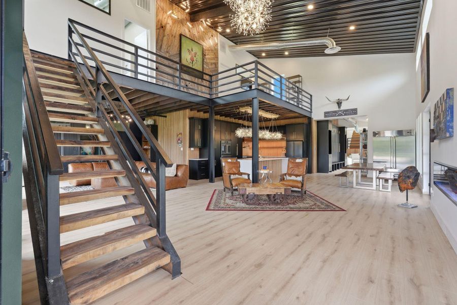 This modern industrial-style home features an open-plan living area with high ceilings and a striking staircase. The space includes a loft, elegant lighting, and a mix of wood and metal accents. The design is both stylish and functional, perfect for contemporary living.