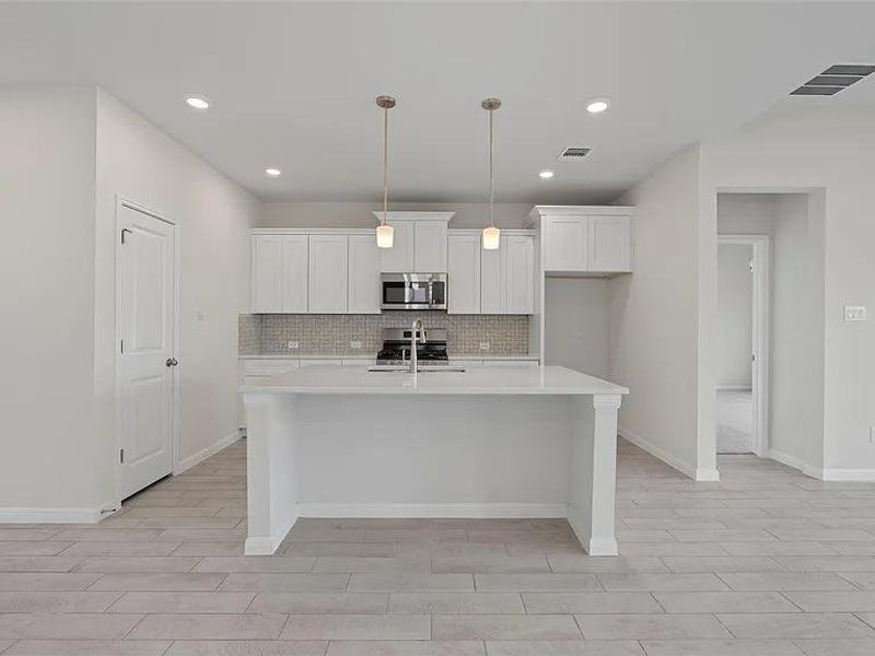 Clean lines and light-toned flooring characterize this modern, well-appointed kitchen with an island.