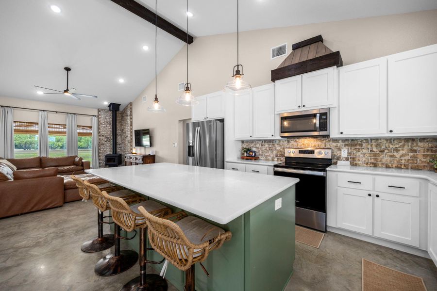 Kitchen featuring a center island, stainless steel appliances, a wood stove, concrete floors, and open floor plan