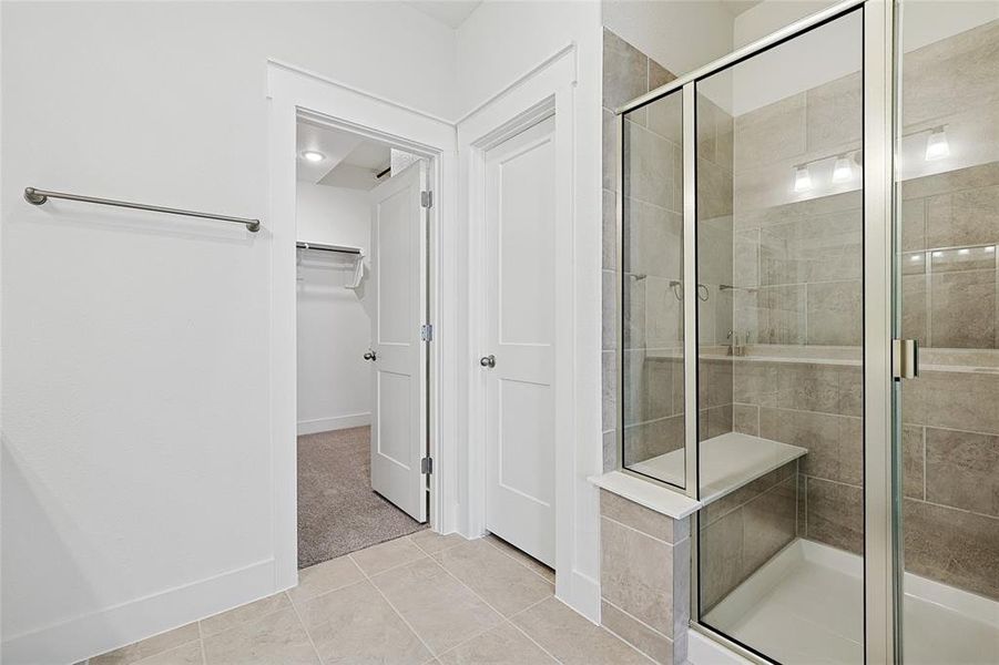 Bathroom with a walk in closet, a shower stall, and light tile patterned floors