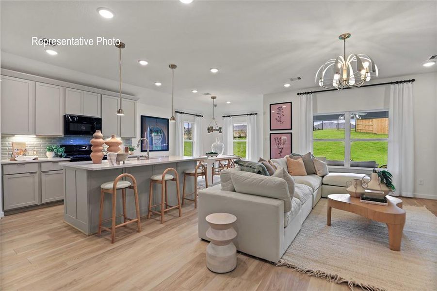 Open-concept living space featuring wood-finish flooring, recessed lighting, and a contemporary chandelier Open-concept living space featuring wood-finish flooring, recessed lighting, and a contemporary chandelier