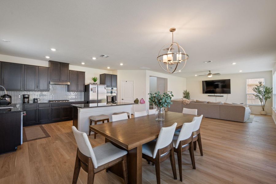 Dining room with hanging lights, light wood finished floors, and ceiling fan