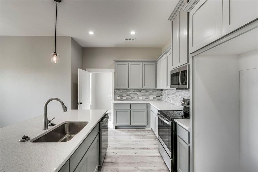 Kitchen featuring light wood-type flooring, appliances with stainless steel finishes, sink, and gray cabinetry