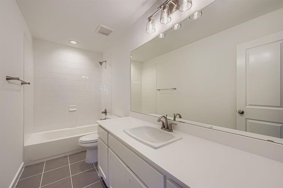 Bathroom featuring dark tile patterned floors, vanity, shower / washtub combination, and recessed lighting Bathroom featuring dark tile patterned floors, vanity, shower / washtub combination, and recessed lighting