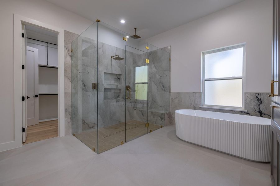 Spa-inspired primary bath showcasing a freestanding soaking tub, oversized glass shower, and elegant modern finishes.