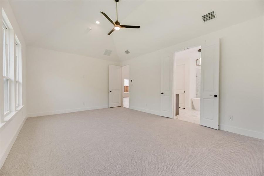 Unfurnished bedroom featuring vaulted ceiling, light carpet, and a ceiling fan Unfurnished bedroom featuring vaulted ceiling, light carpet, and a ceiling fan