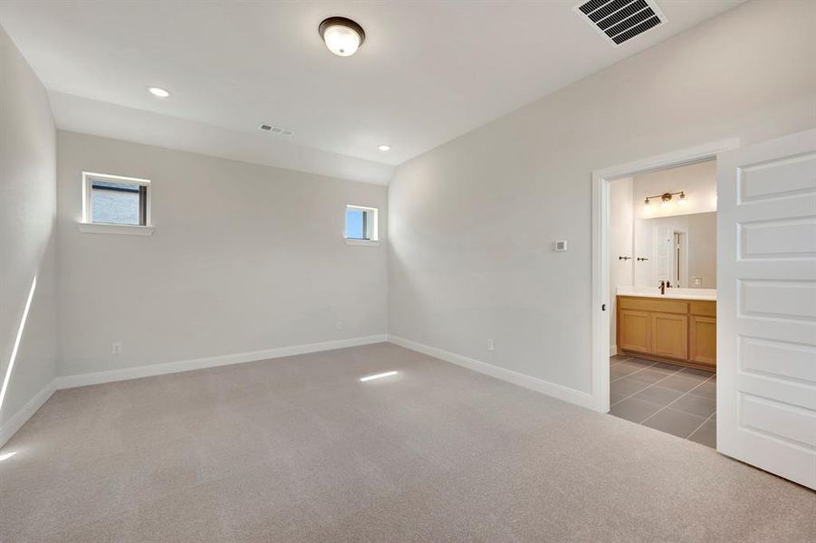 Unfurnished bedroom featuring light carpet, multiple windows, recessed lighting, and connected bathroom