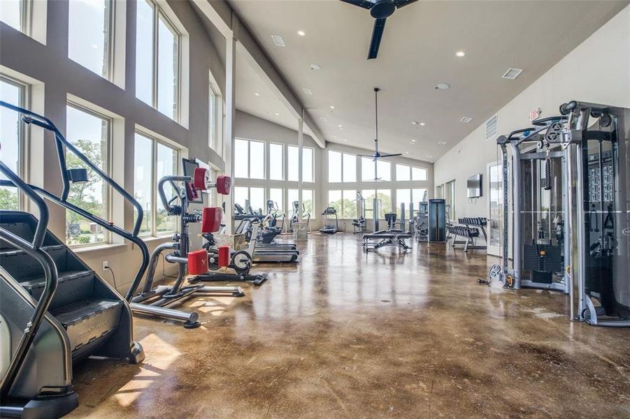 Expansive fitness center featuring high vaulted ceilings, stained concrete flooring, and abundant natural light from numerous windows Expansive fitness center featuring high vaulted ceilings, stained concrete flooring, and abundant natural light from numerous windows