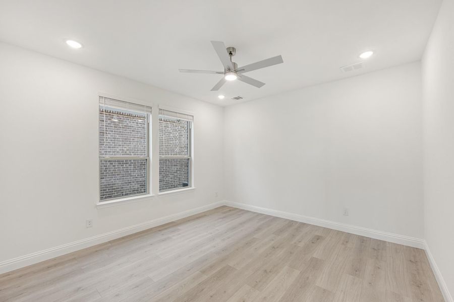 Empty bedroom with light wood floors, ceiling fan, recessed lighting, and two windows Empty bedroom with light wood floors, ceiling fan, recessed lighting, and two windows
