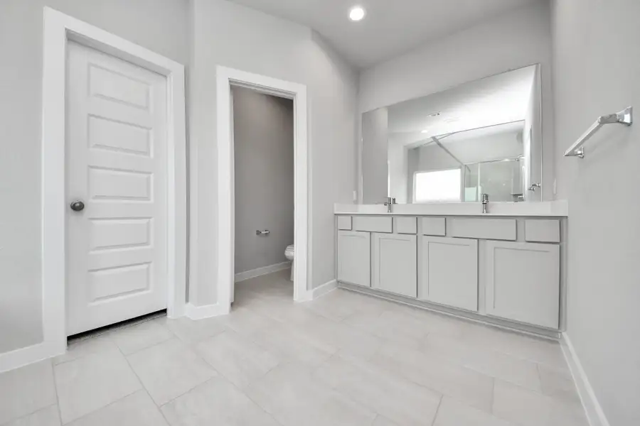 Escape to a spa-like oasis in this primary bathroom. Enjoy a walk-in shower with tile surround, a separate garden tub with custom detailing, and an elegant vanity featuring light countertops, modern hardware, and beautiful vanity lights. Experience luxury and relaxation in every detail. Sample photo of completed home with similar floor plan. Actual colors and selections may vary.