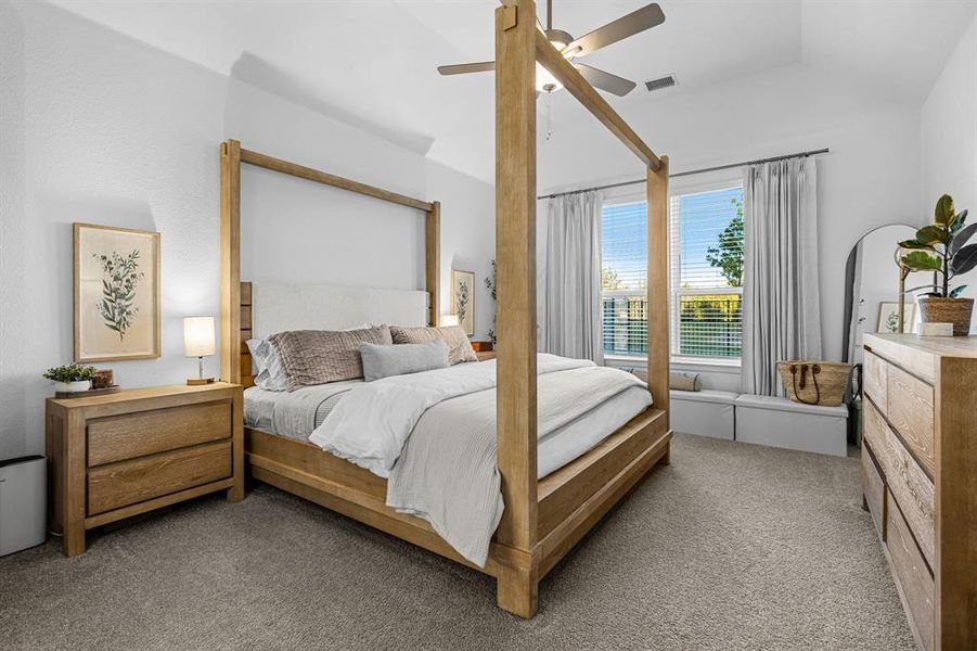 The primary bedroom features a vaulted ceiling and a ceiling fan. The primary bedroom features a vaulted ceiling and a ceiling fan.