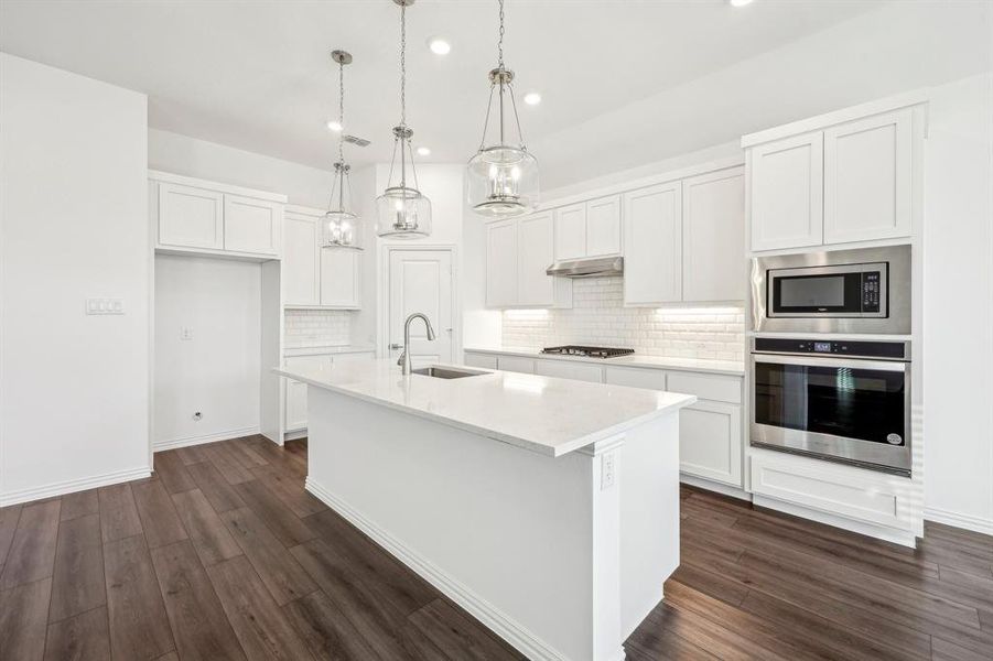 Kitchen with sink, white cabinets, stainless steel appliances, and a kitchen island with sink