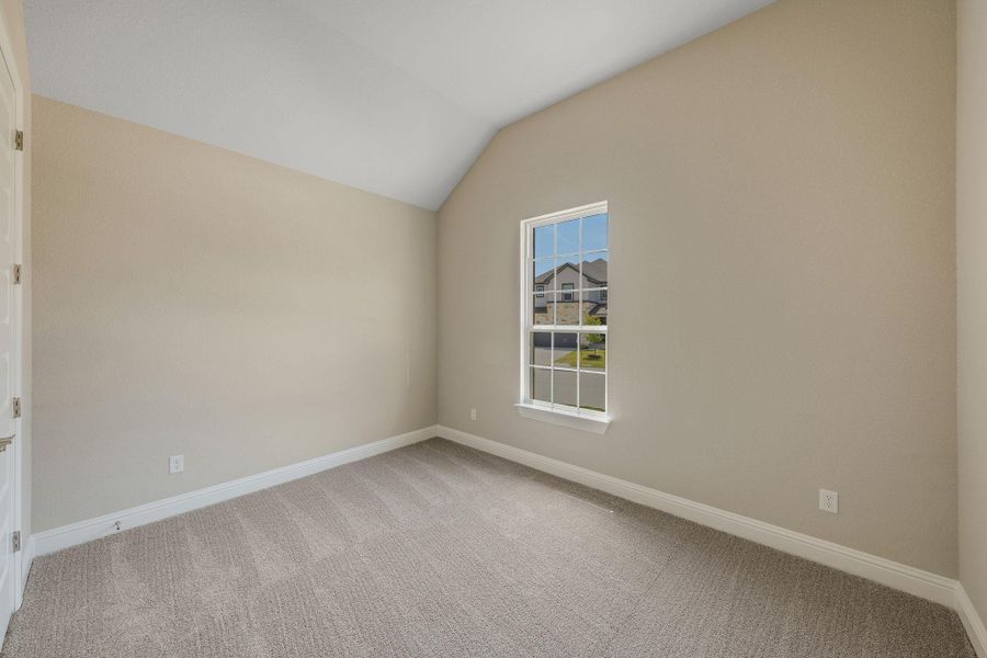 Spare room with vaulted ceiling and light carpet