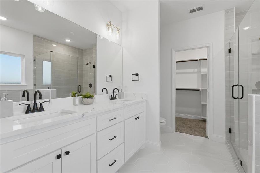 Bathroom featuring double vanity, a spacious closet, a shower stall, light tile patterned floors, and recessed lighting