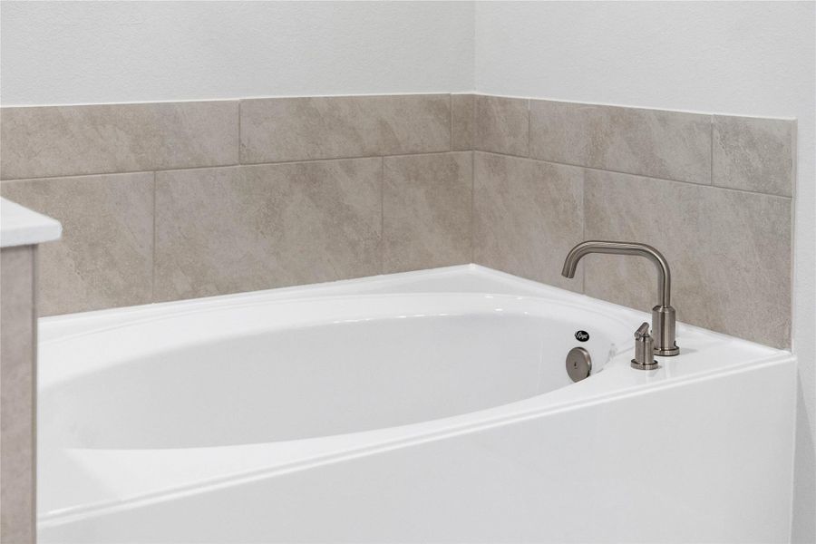 Unwind after a long day in the deep, corner soaking tub, a perfect sanctuary for relaxation. The tub is accented by stylish, warm-toned fixtures.