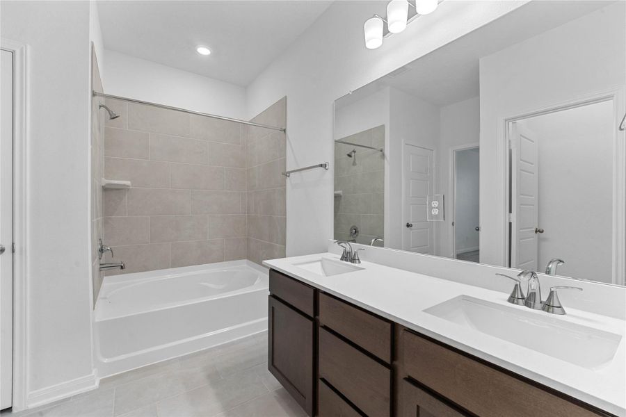 This primary bathroom is definitely move-in ready! Featuring stained cabinets with light countertops, dual vanities, high ceilings, neutral paint, walk-in closet, tub/shower combination with tile surround, sleek and modern finishes.