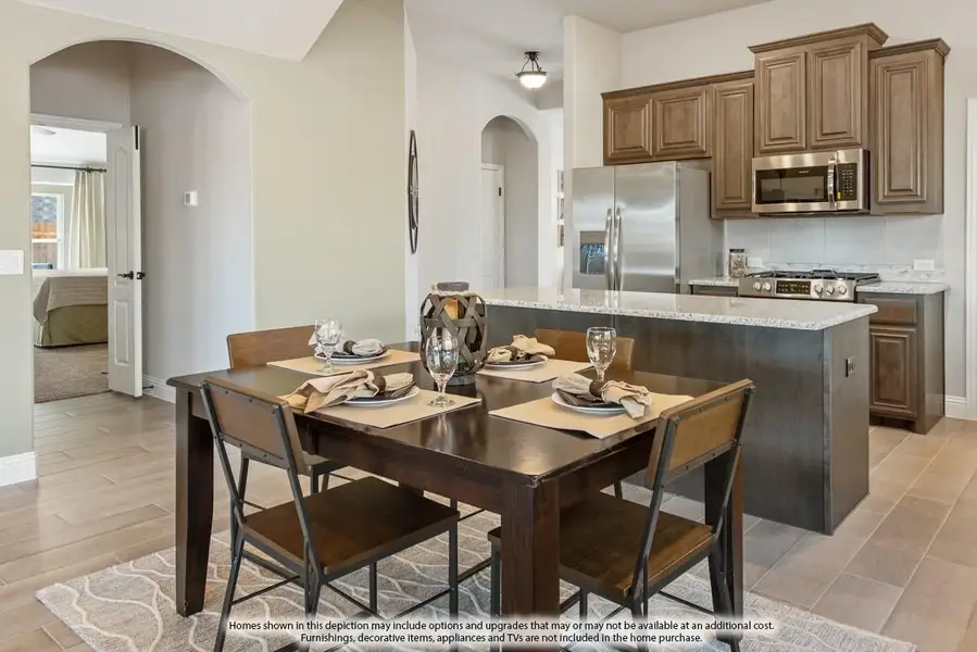 Open dining area with dark wood table and four chairs next to kitchen with brown cabinets and stainless steel appliances