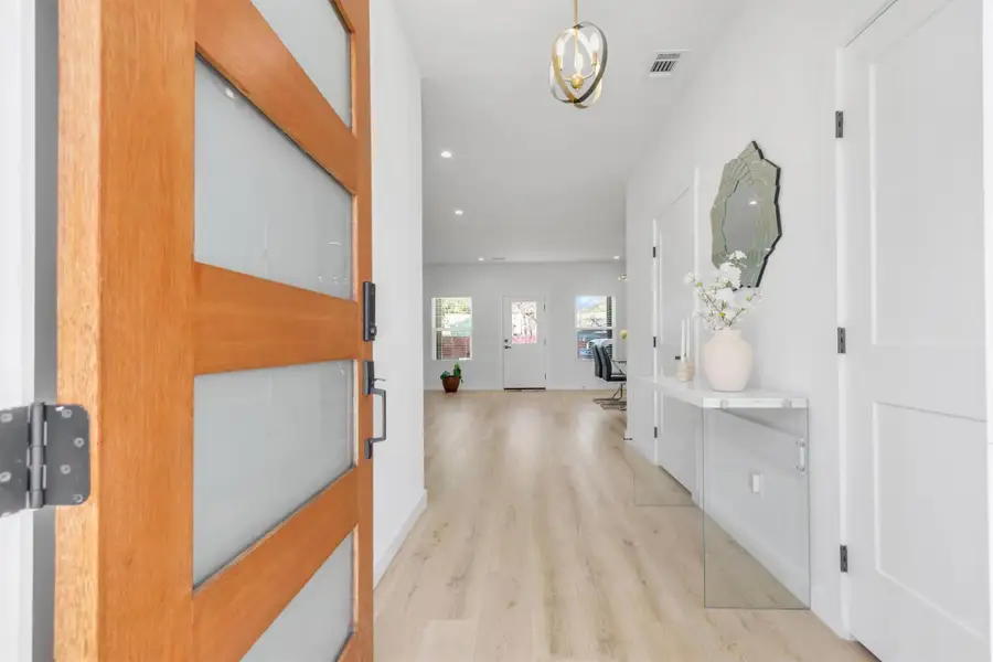 Corridor with light wood-type flooring and suspended lighting