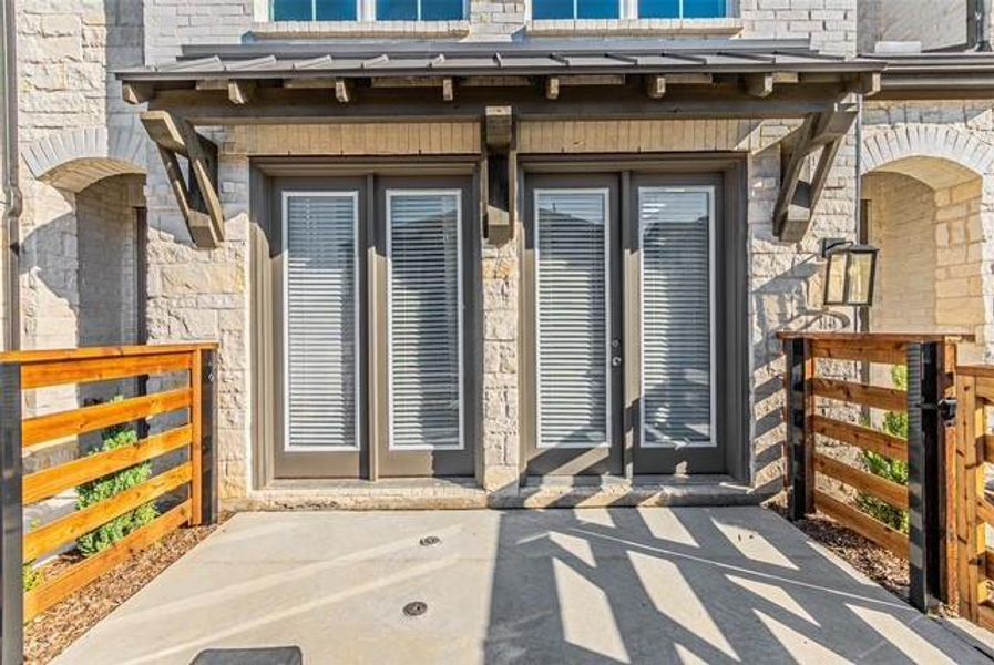 Property entrance with stone siding and a patio area