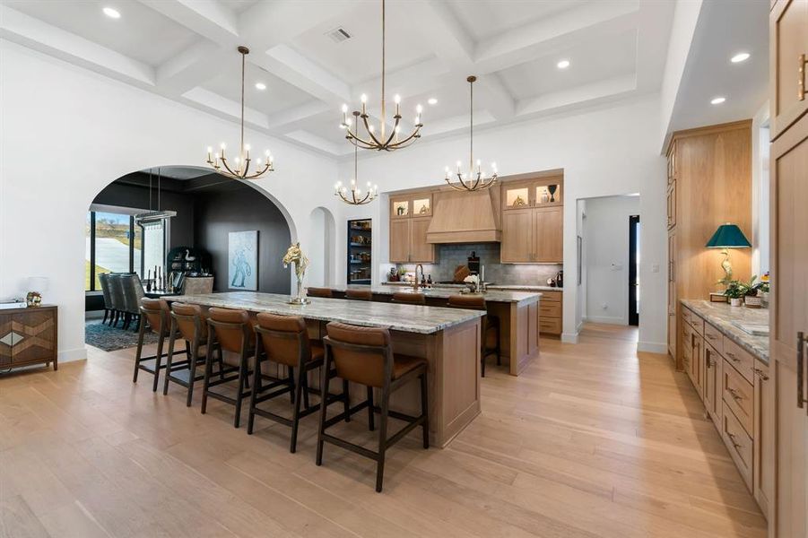 Kitchen with arched walkways, a breakfast bar, a towering ceiling, hanging light fixtures, and light stone countertops Kitchen with arched walkways, a breakfast bar, a towering ceiling, hanging light fixtures, and light stone countertops