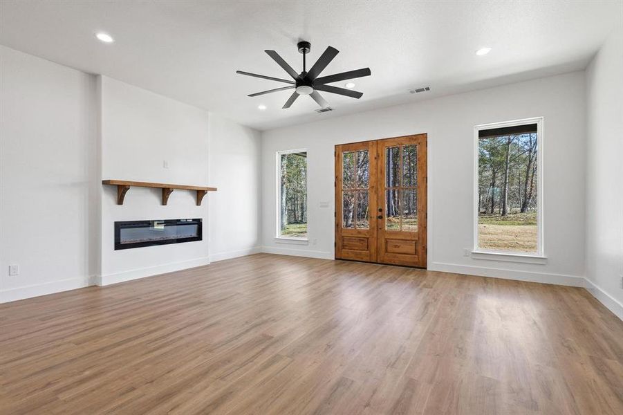 Unfurnished living room with french doors, hardwood / wood-style floors, and ceiling fan