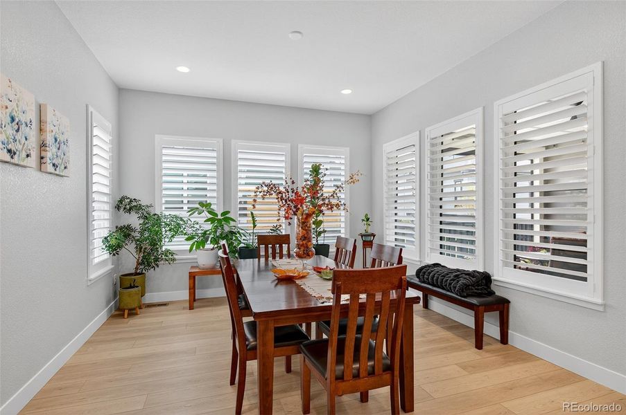 Dining Area – Bright dining space surrounded by large windows with plantation shutters, providing a comfortable setting for meals and gatherings.
