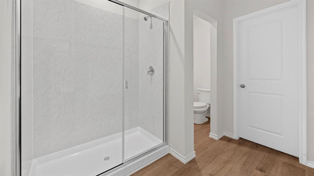 Full bath featuring a shower stall and wood finished floors