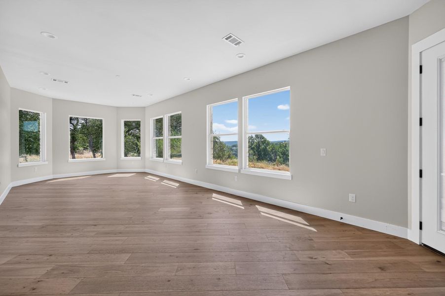 Plentiful windows frame scenic green vistas across this generous open-concept living area with wood floors.