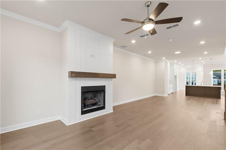 Unfurnished living room with crown molding, recessed lighting, ceiling fan, light wood-style floors, and a fireplace
