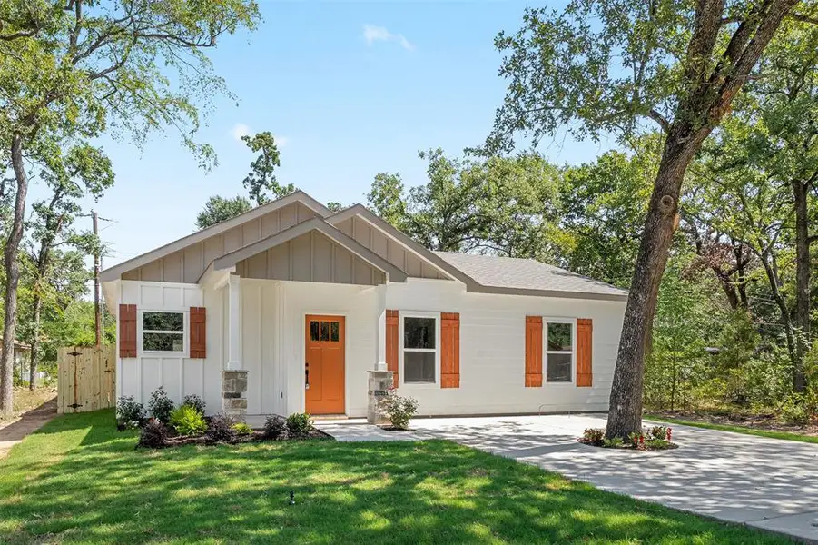 Contemporary-style home featuring white board and batten siding with stone accents