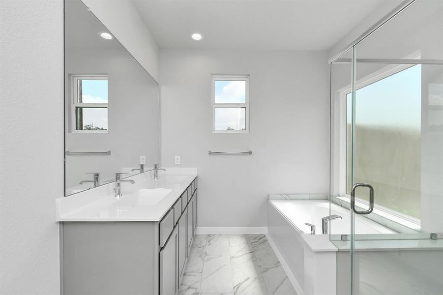 Elevate your daily routine at the refined vanity, now boasting double sinks, light-toned countertops, modern hardware, and bright recessed lights.