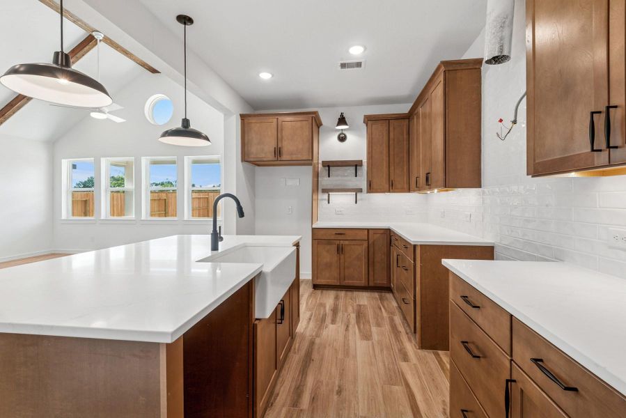Gourmet kitchen with light stain cabinets and quartz countertops