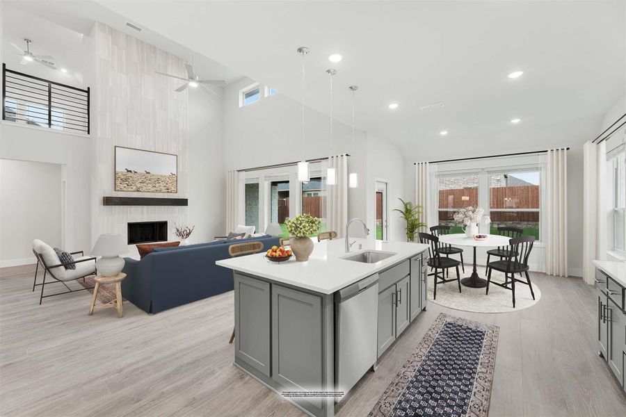 Open-concept kitchen with gray island and white countertop, flowing into living and dining areas with high ceilings