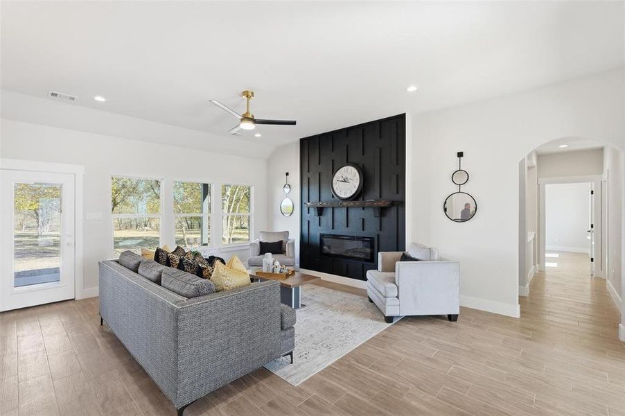 Living room with a fireplace, light wood-style flooring, recessed lighting, a ceiling fan, and arched walkways
